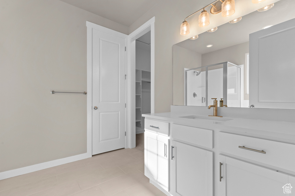 Full bath with tile patterned floors, a stall shower, vanity, baseboards, and a walk in closet