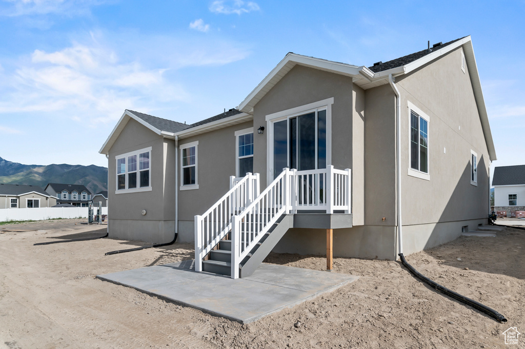 Back of house featuring stucco siding, a mountain view, and a patio