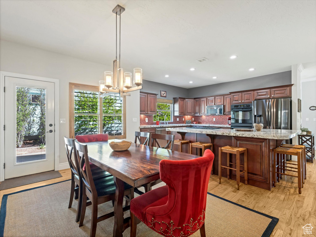 Dining area featuring recessed lighting, light wood-style flooring, and a notable chandelier