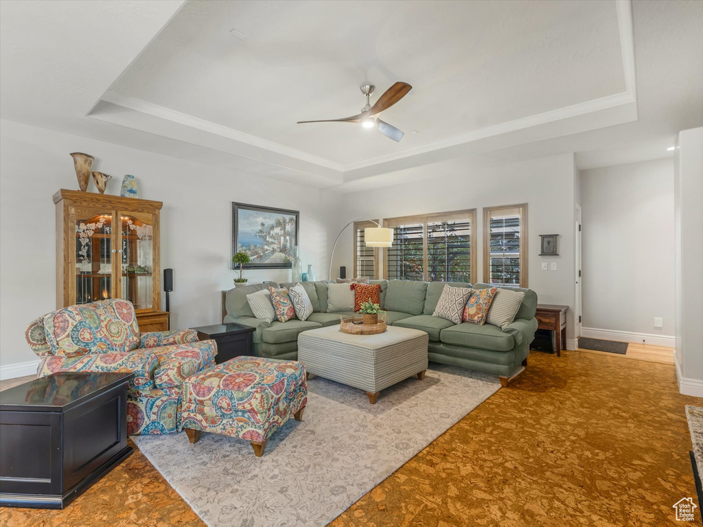 Living room featuring baseboards, ceiling fan, a tray ceiling, and carpet floors