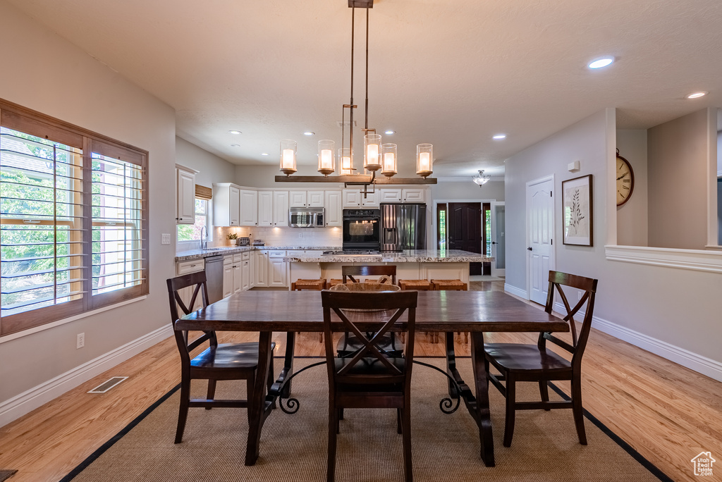 Dining room with light wood-style floors and recessed lighting