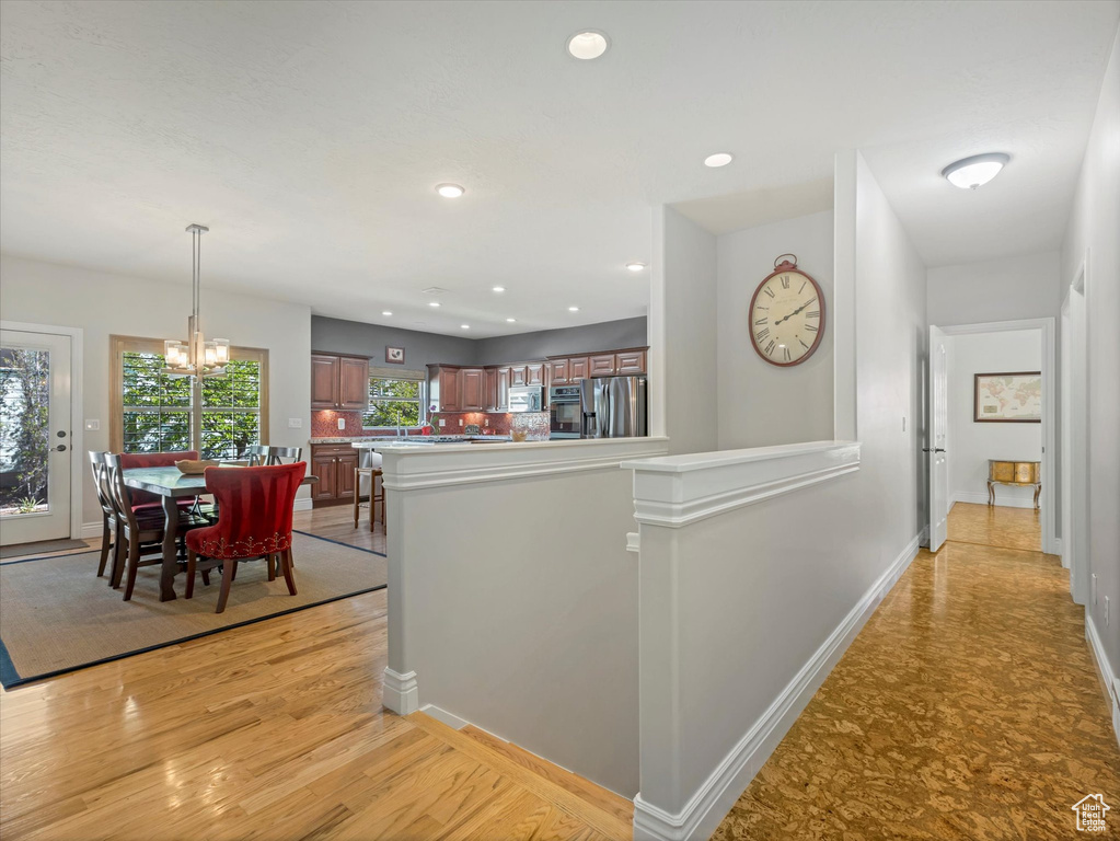 Hall with a notable chandelier, light wood-type flooring, baseboards, an upstairs landing, and recessed lighting