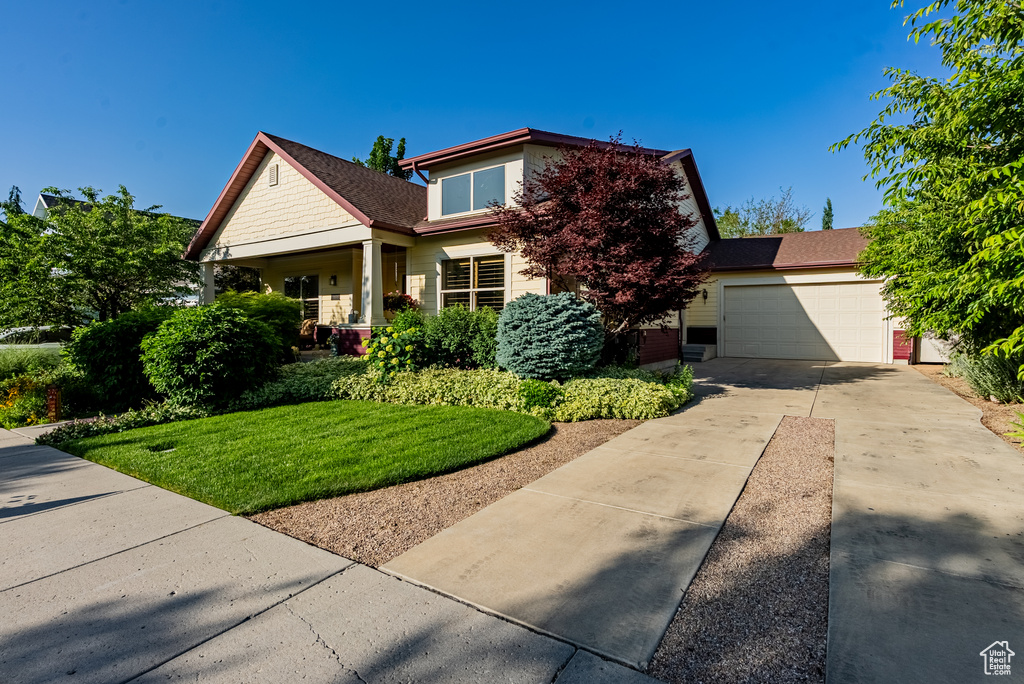 View of front facade featuring driveway, an attached garage, and a front yard