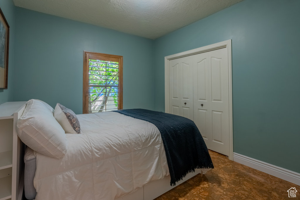 Bedroom with a closet, a textured ceiling, and carpet