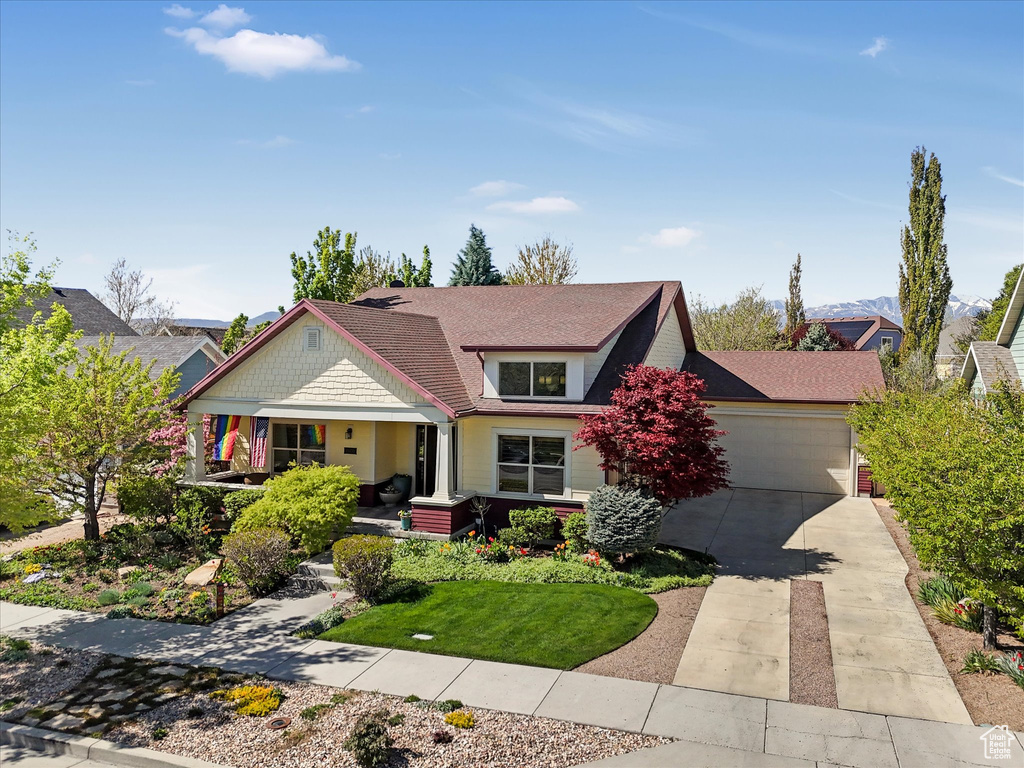 View of front of property featuring a porch, a garage, roof with shingles, and driveway