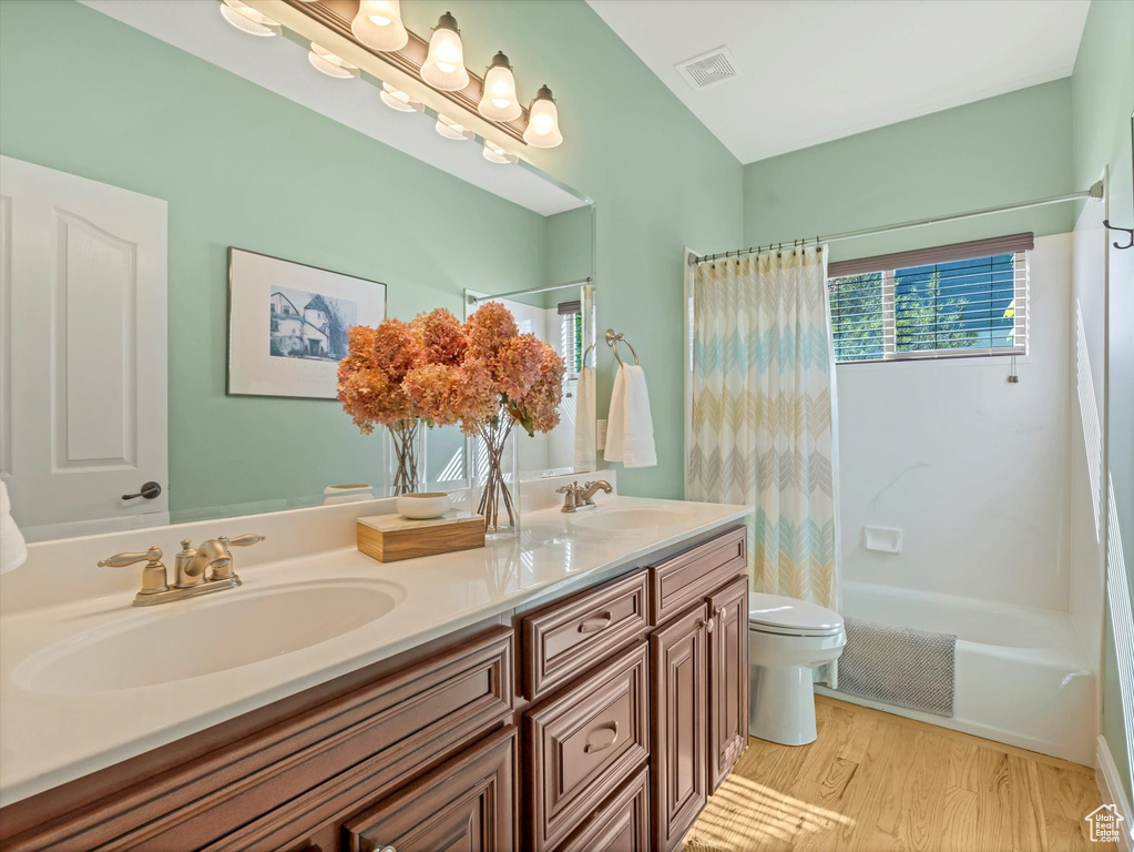 Bathroom with toilet, visible vents, a sink, and wood finished floors