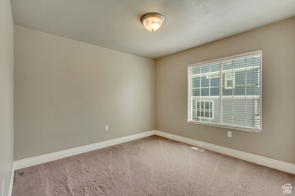 Carpeted empty room featuring baseboards and visible vents