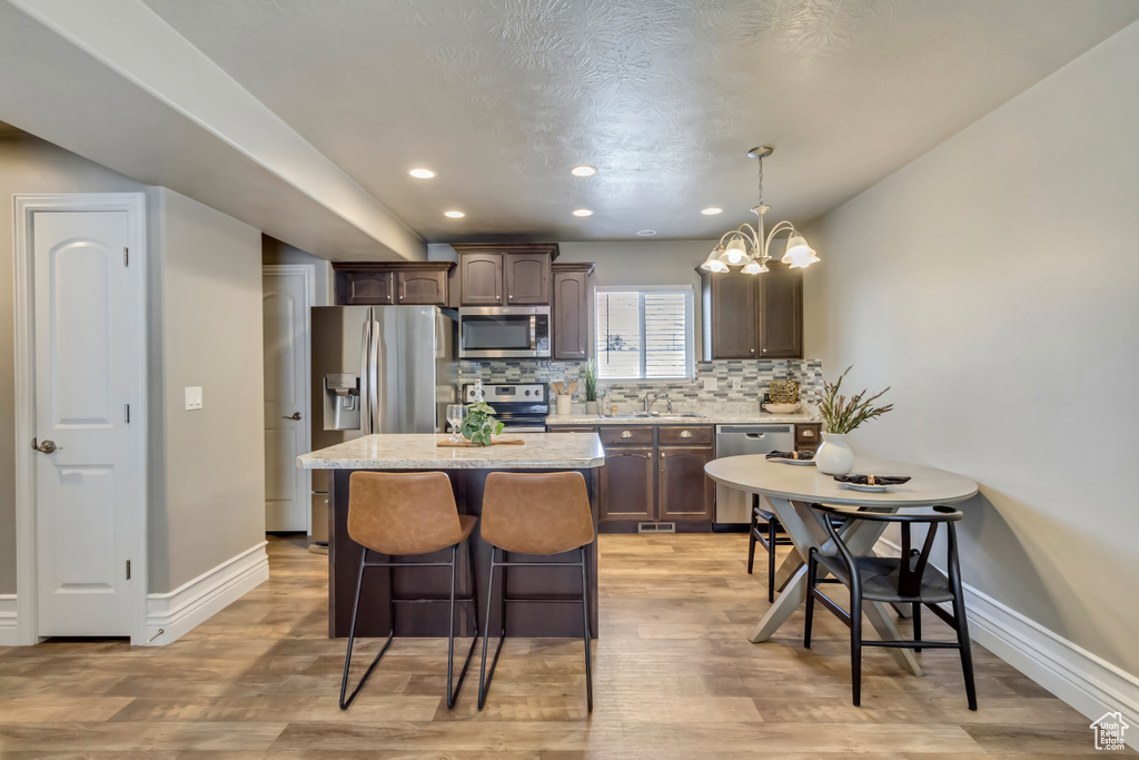 Kitchen with baseboards, a center island, dark brown cabinets, and appliances with stainless steel finishes