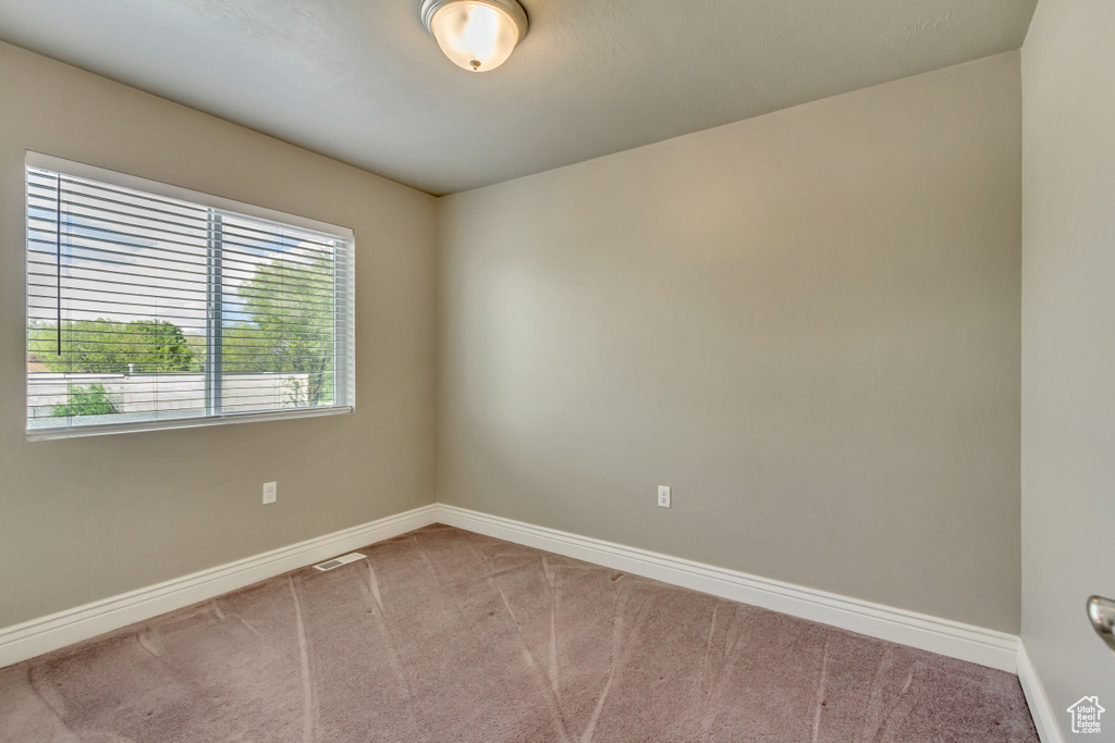 Carpeted spare room with visible vents and baseboards