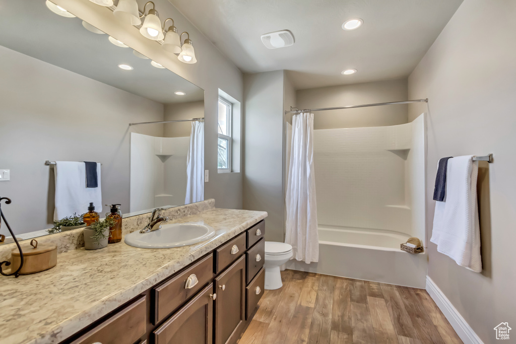 Bathroom featuring recessed lighting, wood finished floors, shower / bath combo, toilet, and vanity