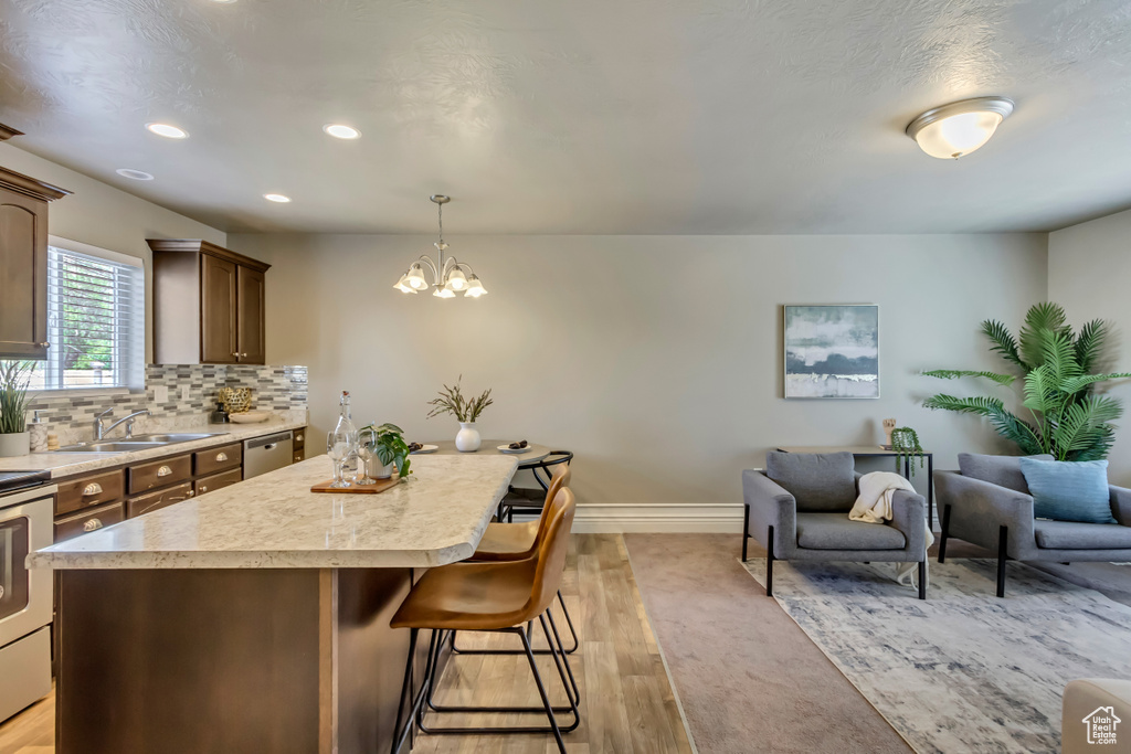 Kitchen featuring a sink, a breakfast bar, light countertops, baseboards, and recessed lighting