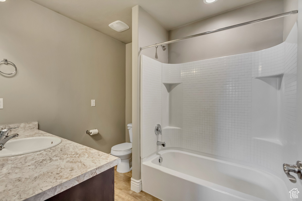 Bathroom with vanity, bathing tub / shower combination, toilet, baseboards, and wood finished floors