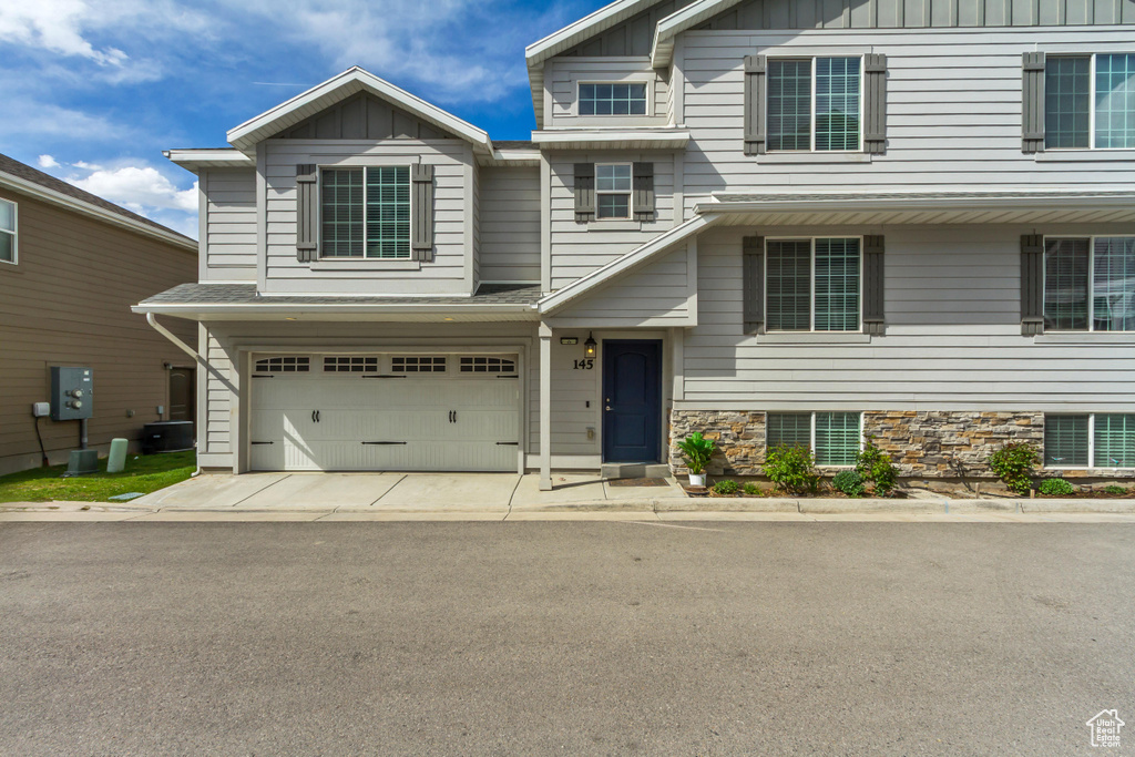 View of front of property featuring board and batten siding, concrete driveway, and an attached garage