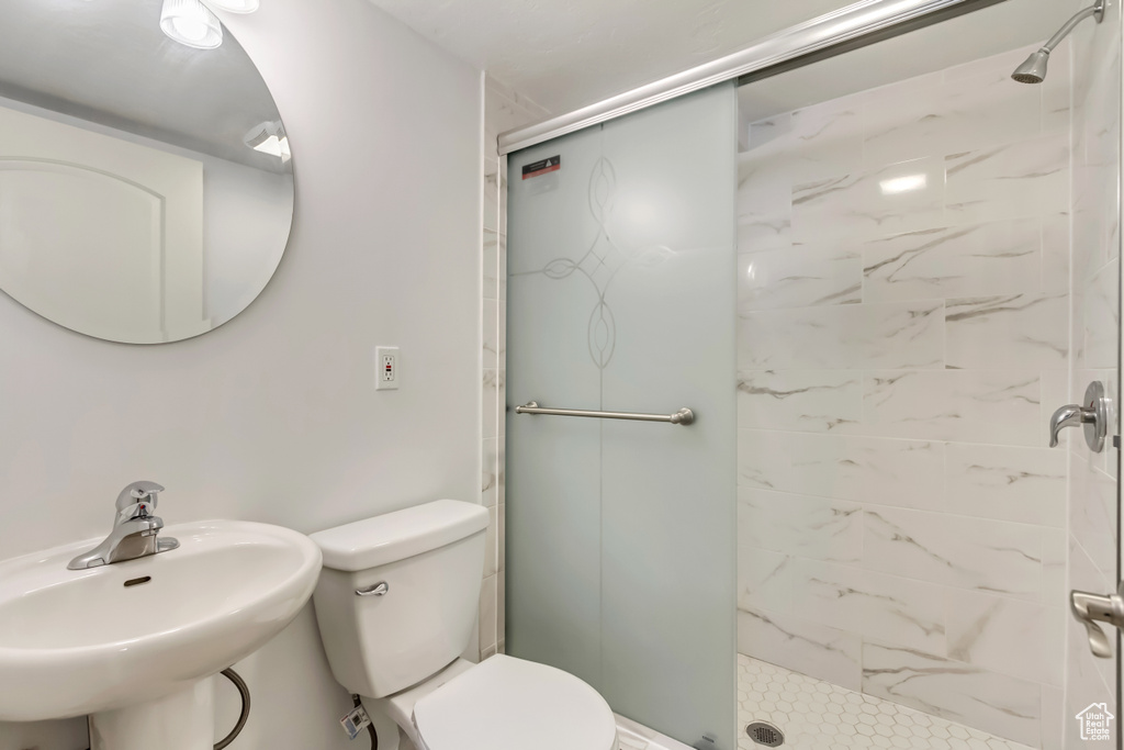Full bath with toilet, a stall shower, and a sink