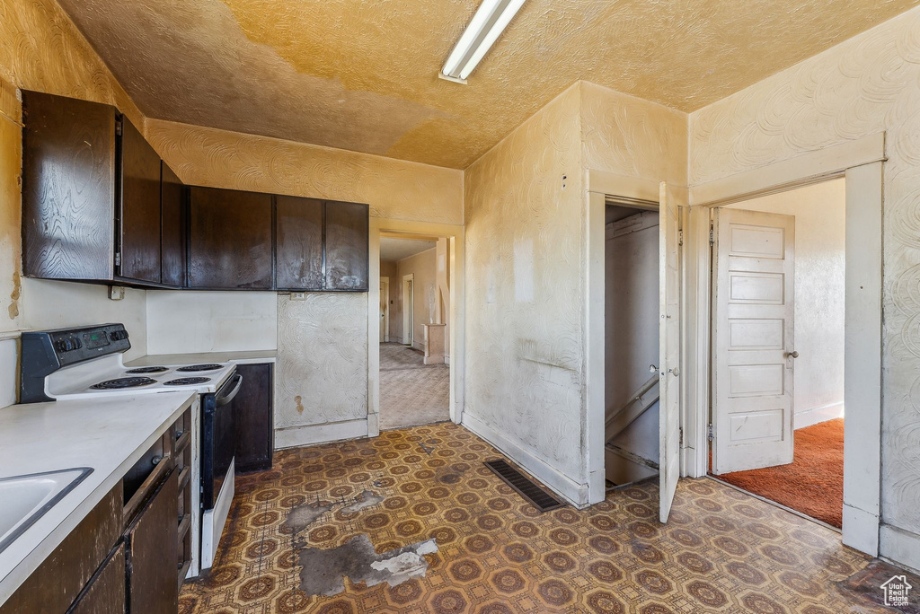 Kitchen featuring light countertops, dark brown cabinetry, visible vents, and range with electric stovetop