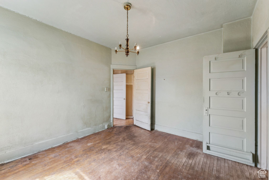 Spare room with baseboards, a notable chandelier, and wood finished floors
