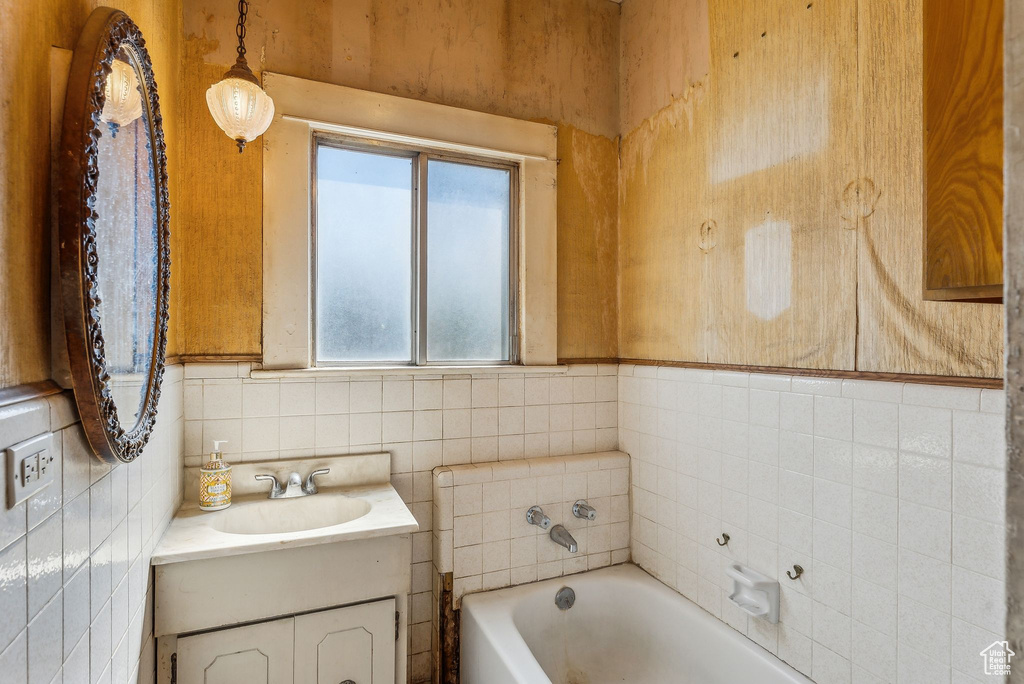 Bathroom with a garden tub, tile walls, and vanity