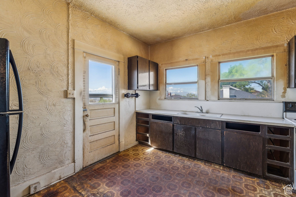 Kitchen with a sink, dark floors, dark brown cabinets, and light countertops