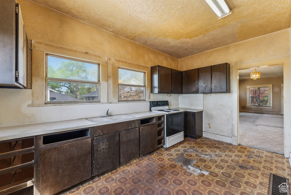 Kitchen featuring a sink, dark brown cabinets, white range with electric cooktop, and light countertops