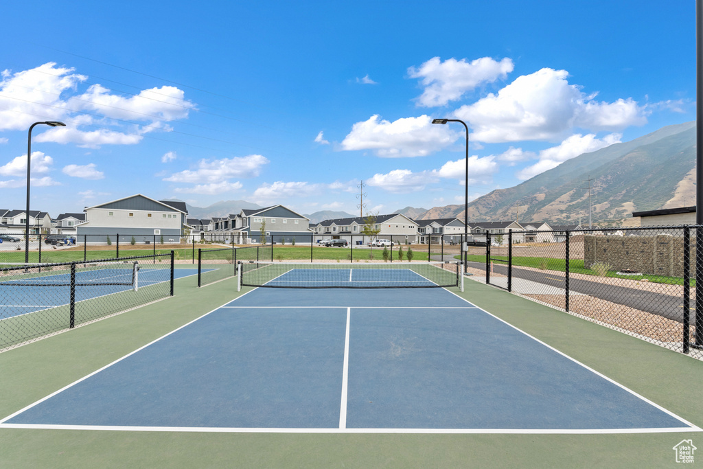 View of tennis court with a residential view, fence, and a mountain view