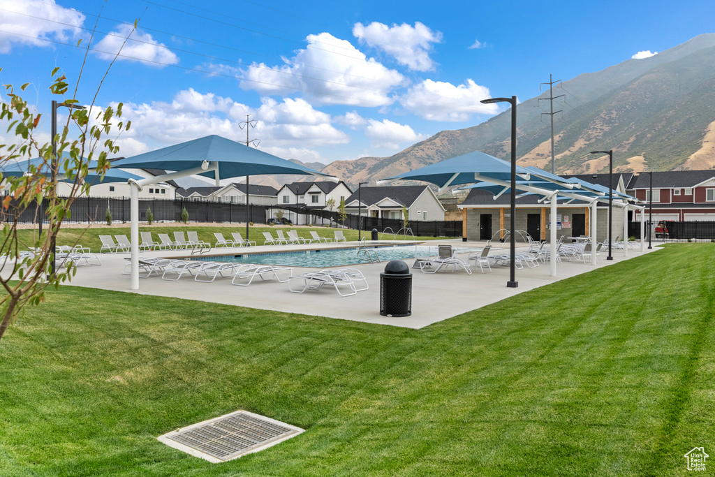 Community pool featuring a lawn, fence, a mountain view, and a patio area