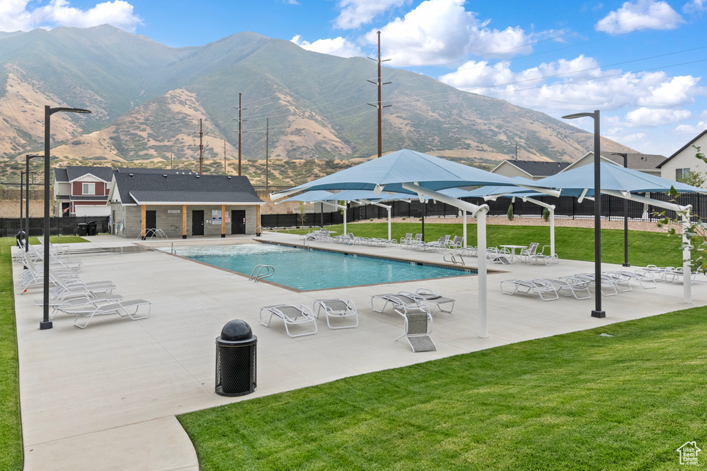 Community pool featuring fence, a lawn, and a patio area