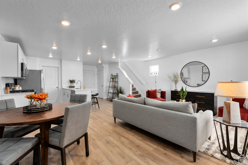 Living room with stairway, light wood finished floors, and recessed lighting