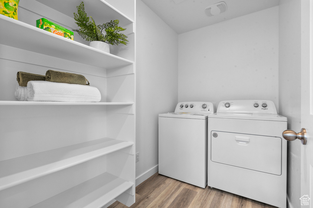 Clothes washing area featuring laundry area, visible vents, washer and dryer, baseboards, and light wood-type flooring