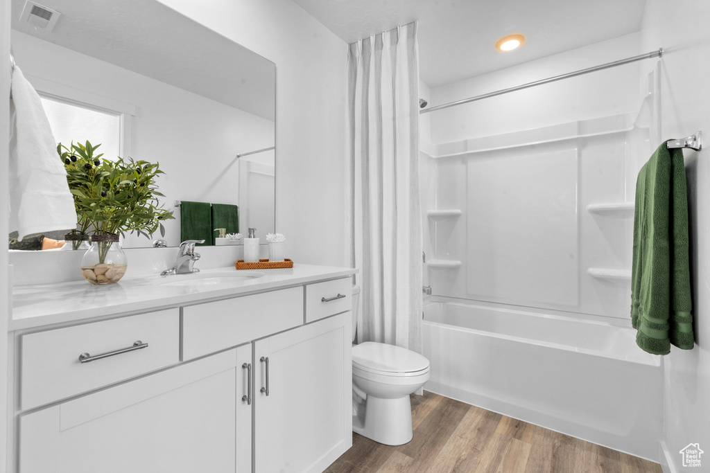Bathroom with visible vents, vanity, wood finished floors, shower / bath combination with curtain, and toilet