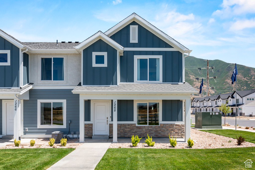 View of front of house with board and batten siding, central AC, and a front lawn