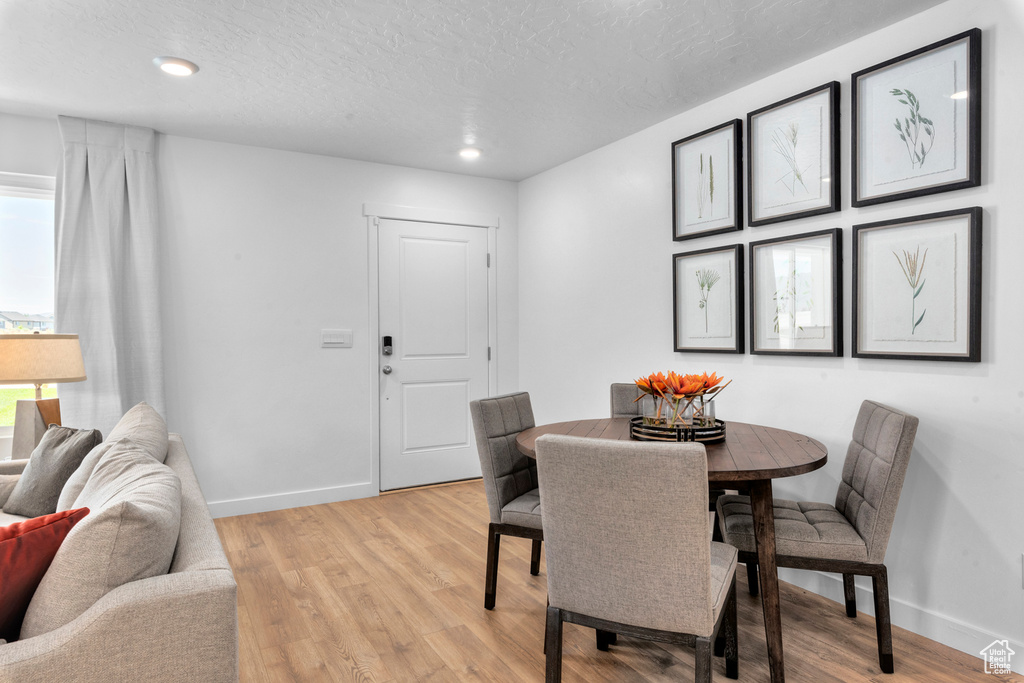 Dining area featuring baseboards, a textured ceiling, light wood-style floors, and recessed lighting