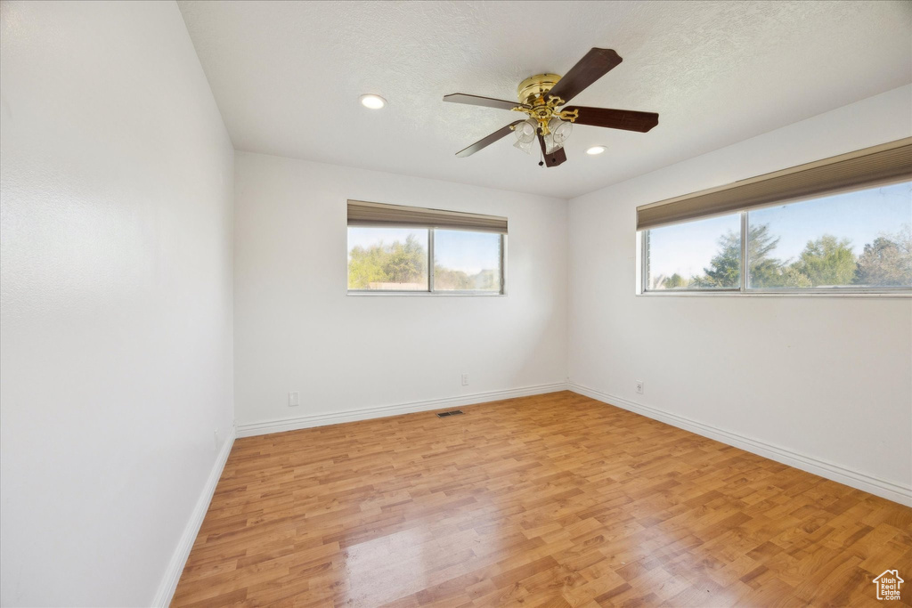 Empty room with visible vents, baseboards, light wood-type flooring, recessed lighting, and a ceiling fan