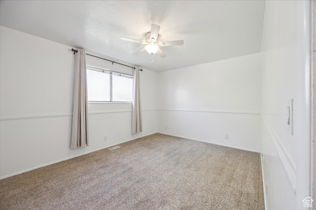 Carpeted spare room with baseboards, ceiling fan, and visible vents