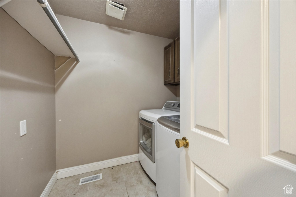 Laundry room featuring visible vents, washer and clothes dryer, cabinet space, and baseboards