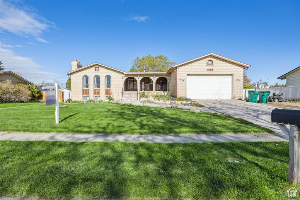 Mediterranean / spanish-style home featuring covered porch, a chimney, a garage, a front lawn, and concrete driveway