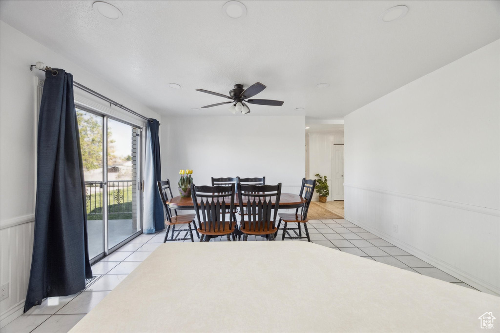 Dining area with a ceiling fan, wainscoting, and light tile patterned floors