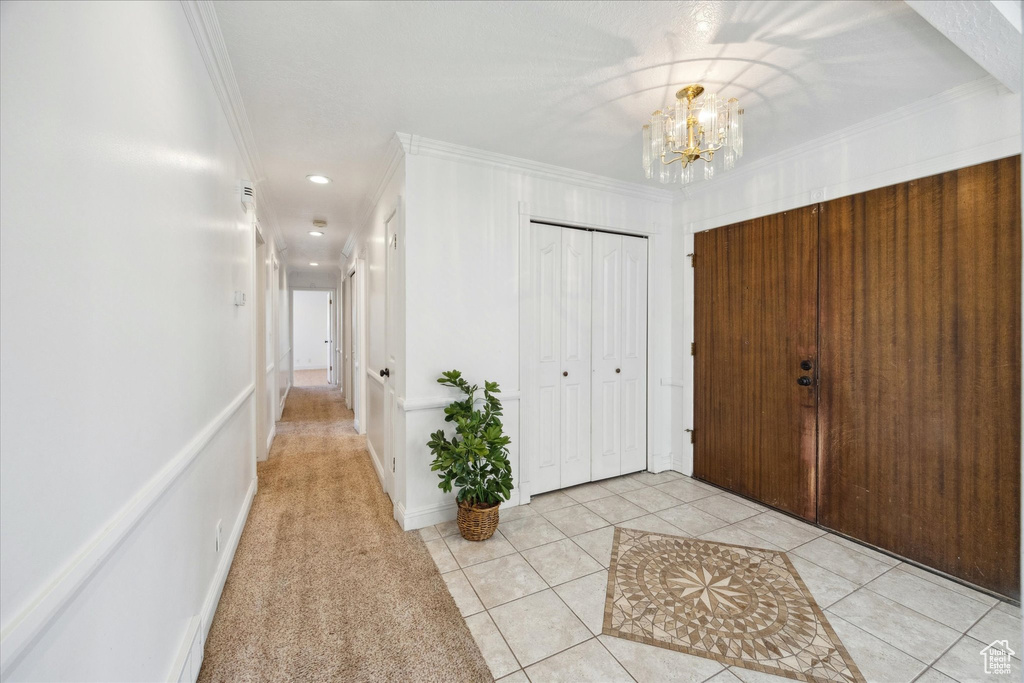 Foyer with recessed lighting, an inviting chandelier, ornamental molding, and light tile patterned floors