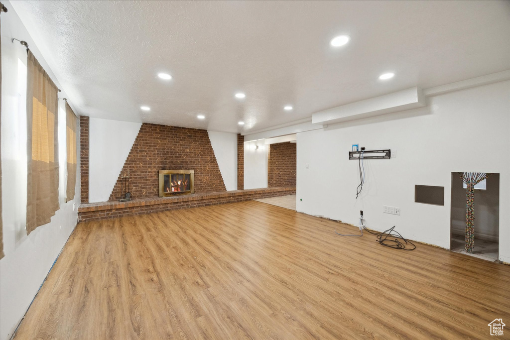 Below grade area with recessed lighting, light wood finished floors, and a fireplace