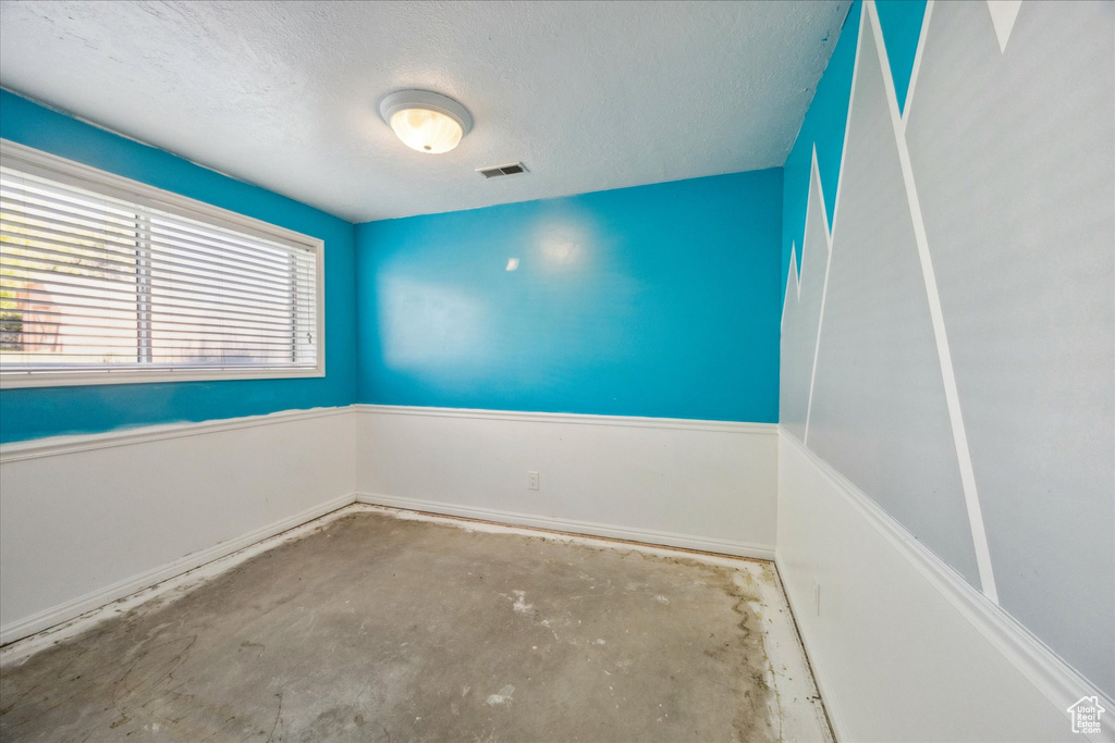 Unfurnished room with visible vents, a textured ceiling, baseboards, and unfinished concrete floors