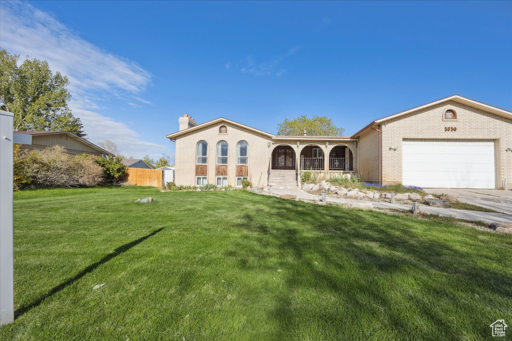 Mediterranean / spanish-style home featuring covered porch, a chimney, a front yard, and a garage