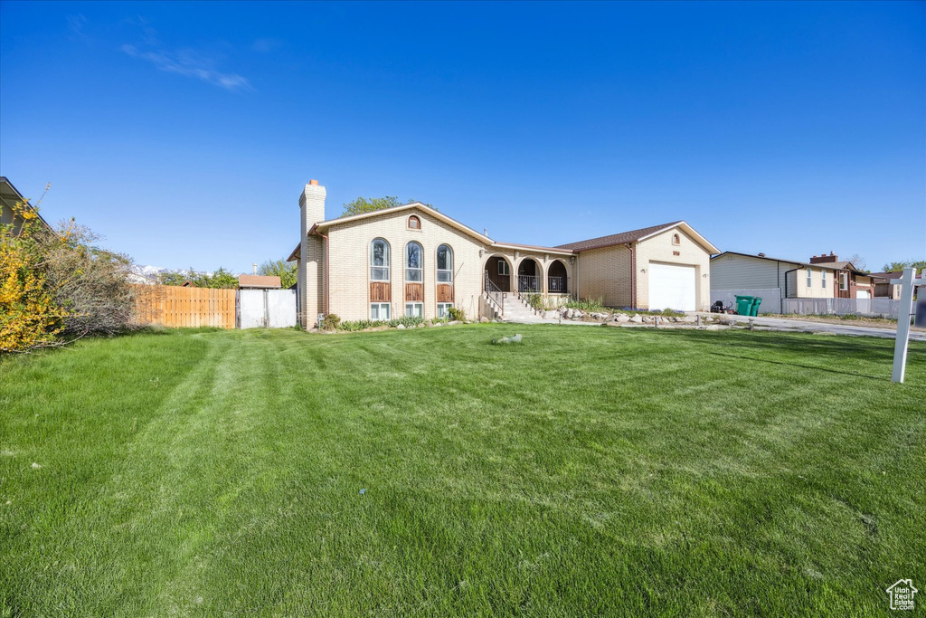 Rear view of house with a lawn, fence, a chimney, and a garage