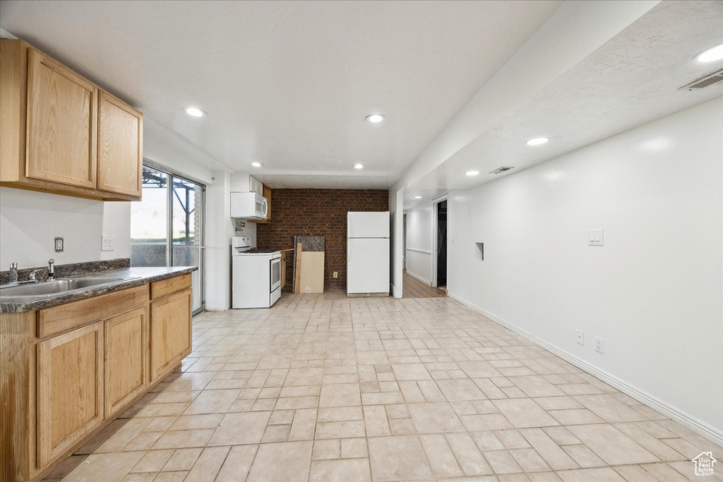 Kitchen featuring recessed lighting, a sink, dark countertops, and white appliances