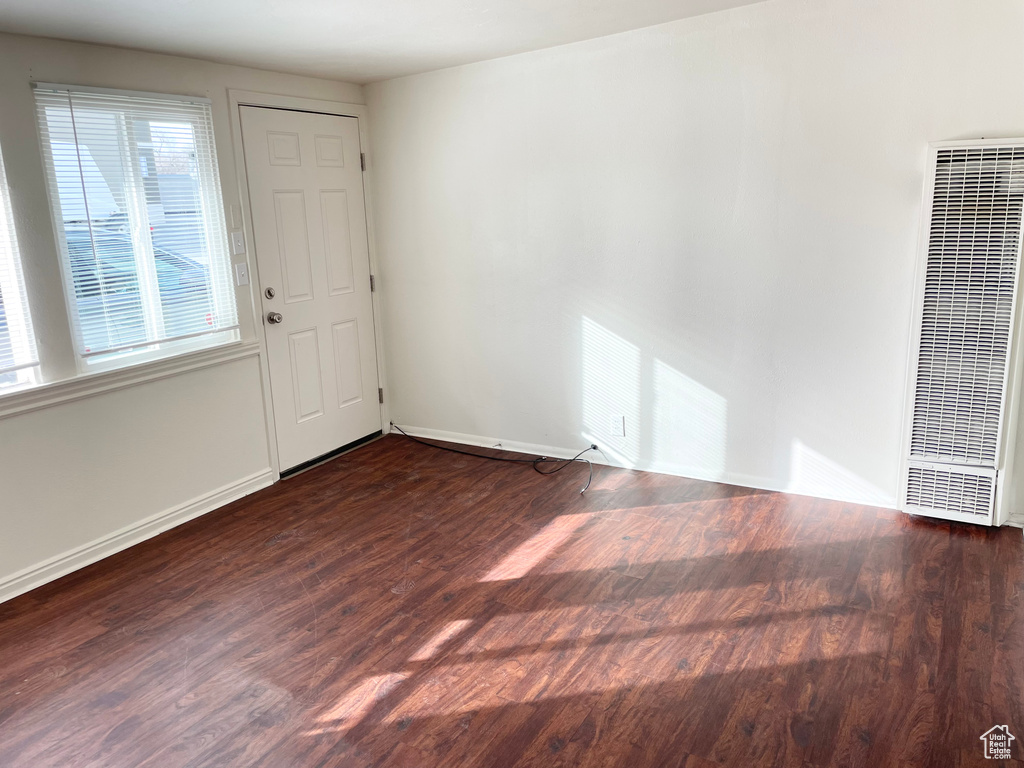 Unfurnished room featuring baseboards, wood finished floors, and a heating unit