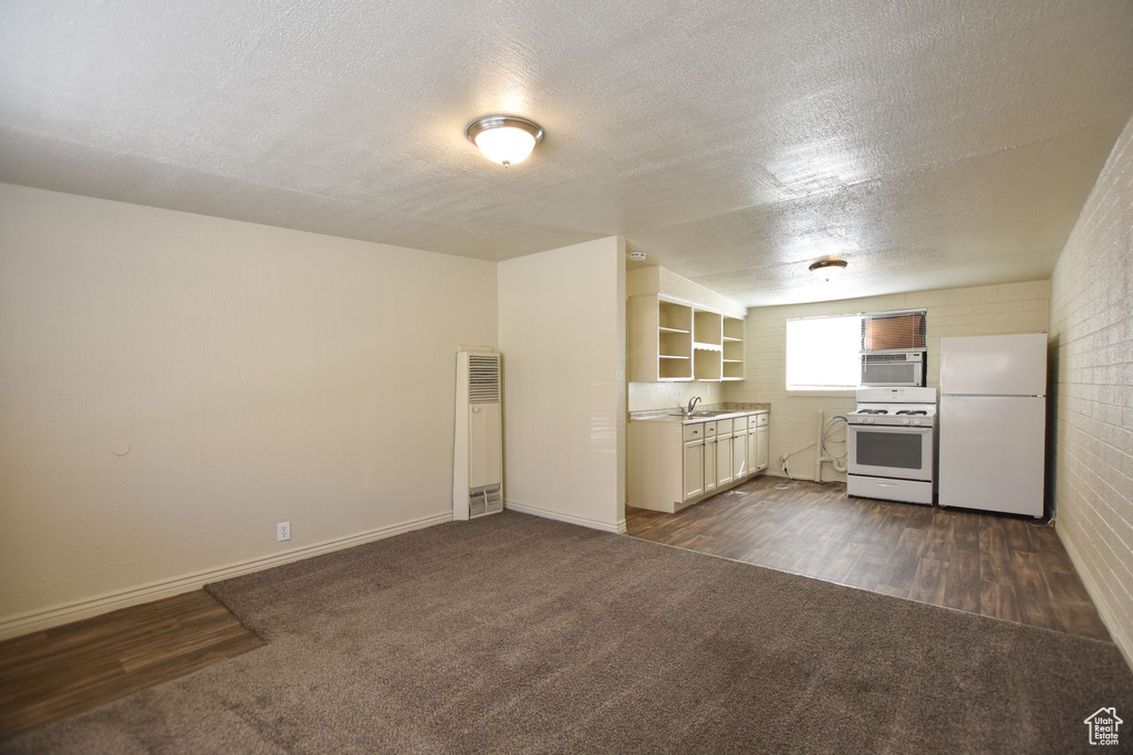 Kitchen with open shelves, a sink, dark colored carpet, white appliances, and a heating unit