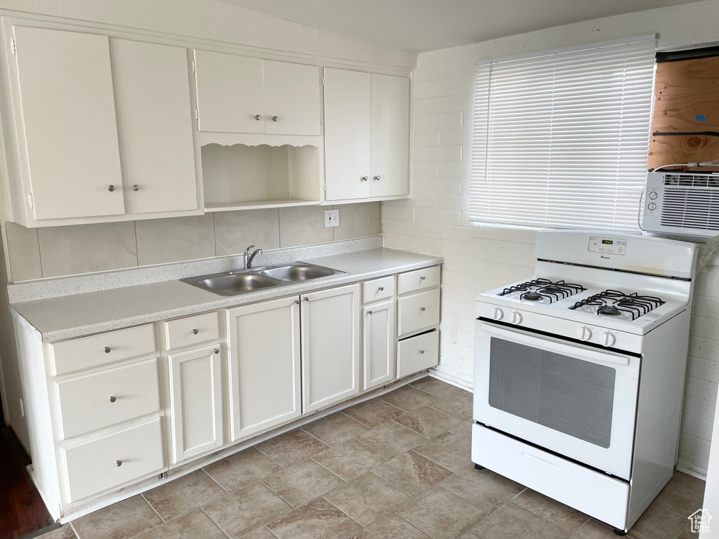 Kitchen featuring light countertops, white cabinetry, a sink, and gas range gas stove