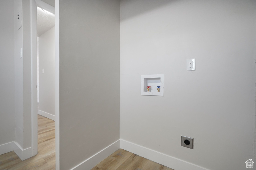 Washroom with electric dryer hookup, hookup for a washing machine, baseboards, and light wood-type flooring