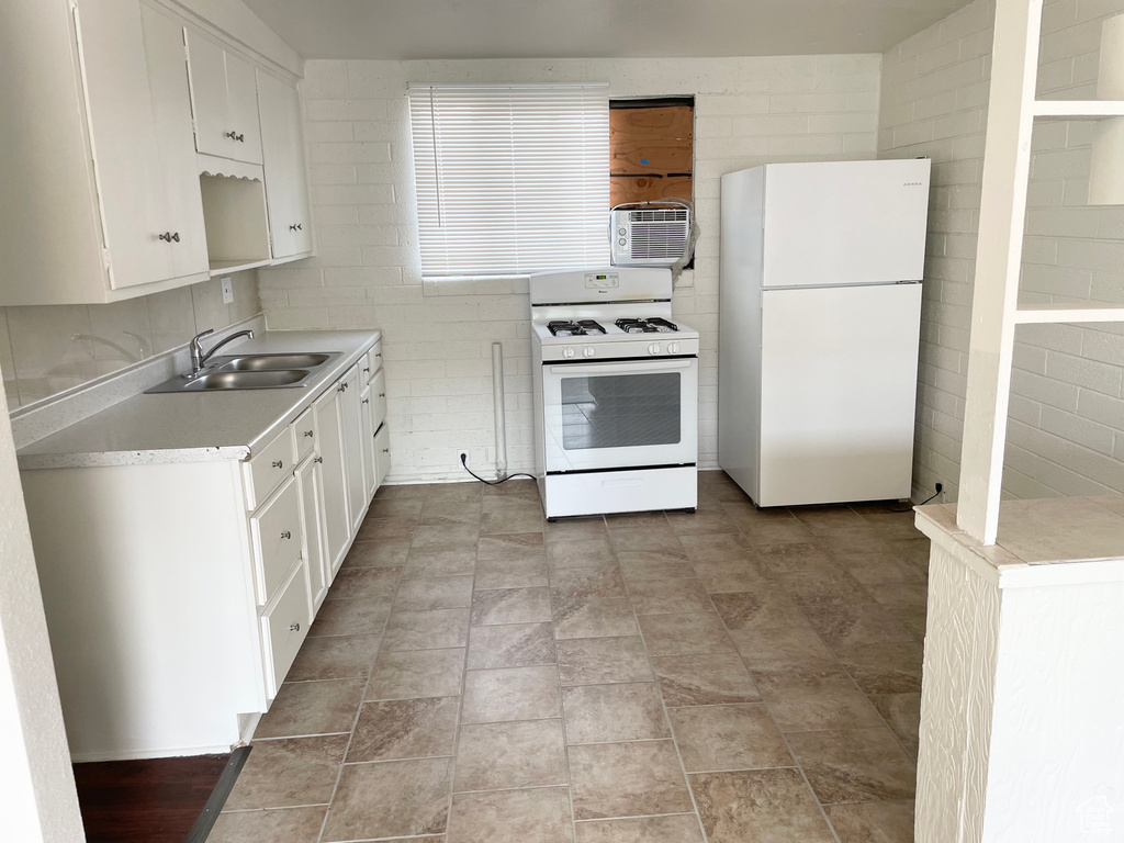 Kitchen featuring a sink, white cabinetry, white appliances, and light countertops