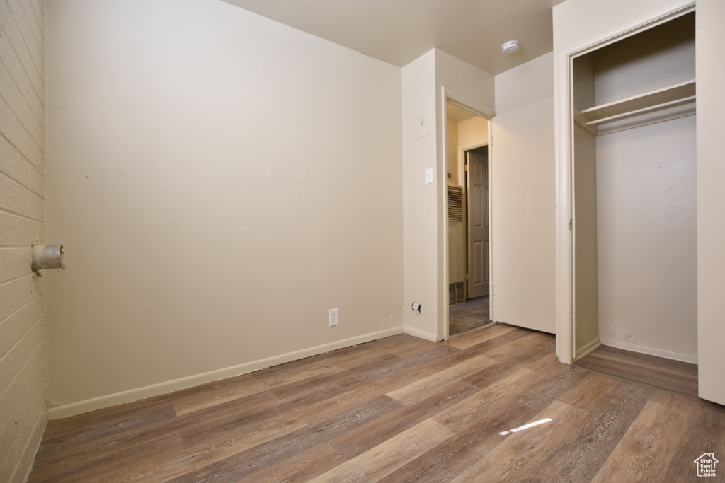 Unfurnished bedroom featuring baseboards, wood finished floors, and a closet