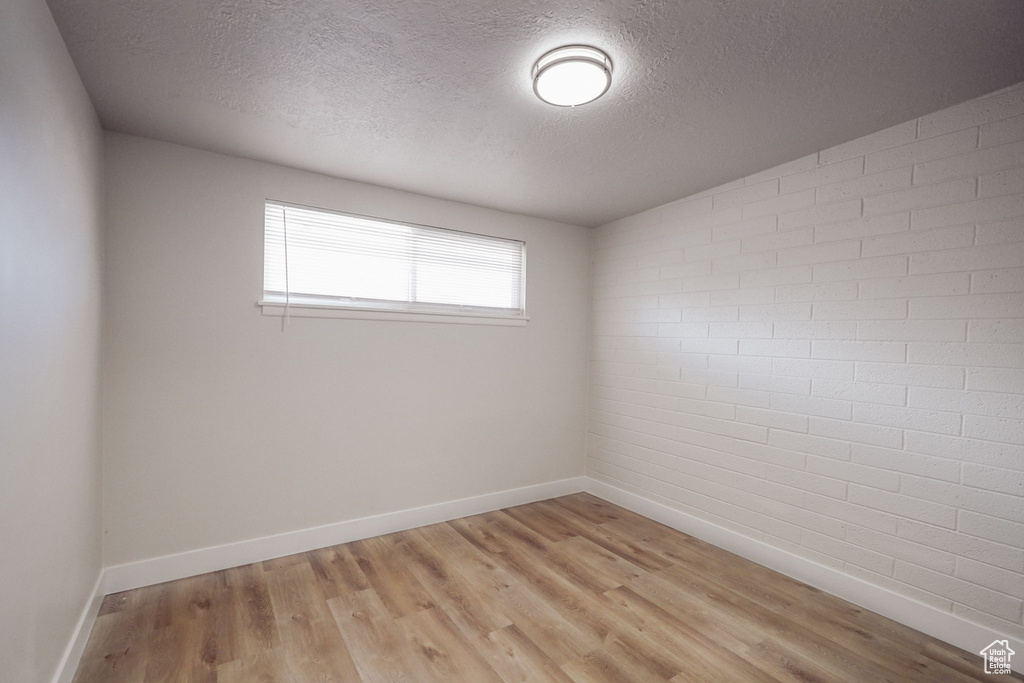 Spare room featuring light wood-type flooring, a textured ceiling, and baseboards