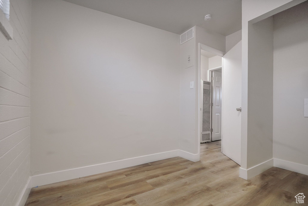 Unfurnished room with light wood-type flooring, a heating unit, baseboards, and visible vents